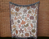 Fall woven blanket with cream background draped over couch